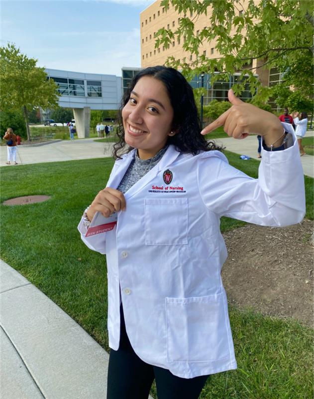 Annaly Garcia poses with her white coat outside of Cooper Hall
