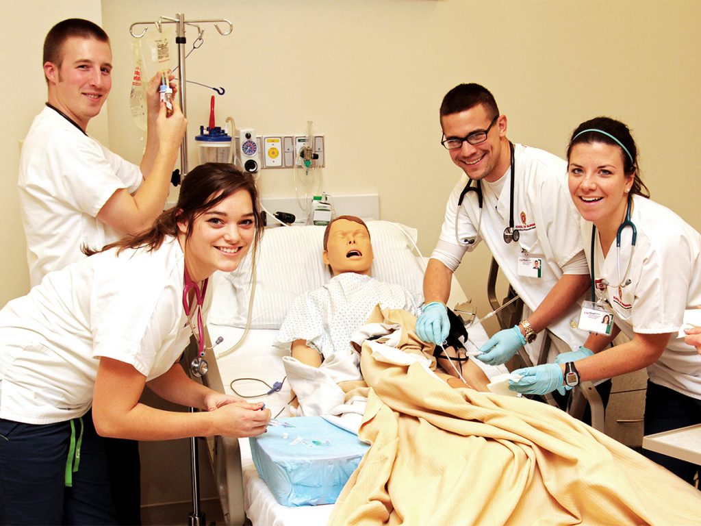 Students in the Doctor of Nursing Practice program stand around a mannequin patient.