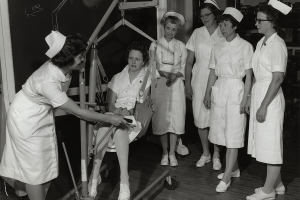 Barbara Gessner ’64, PhD’79 (left) demonstrates the use of a Hoyer lift to nurses enrolled in a refresher course, circa 1963. An acute shortage of nurses in Wisconsin, caused by nurses leaving the field to raise families, created a need for increased educational opportunities for continuing education. Nurses who had left the workforce attended courses such as this when they were ready to return to practice. 