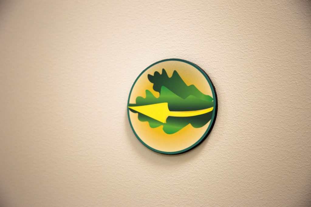 A yellow arrow against green leaves points the way along Cooper Hall's indoor walking path.