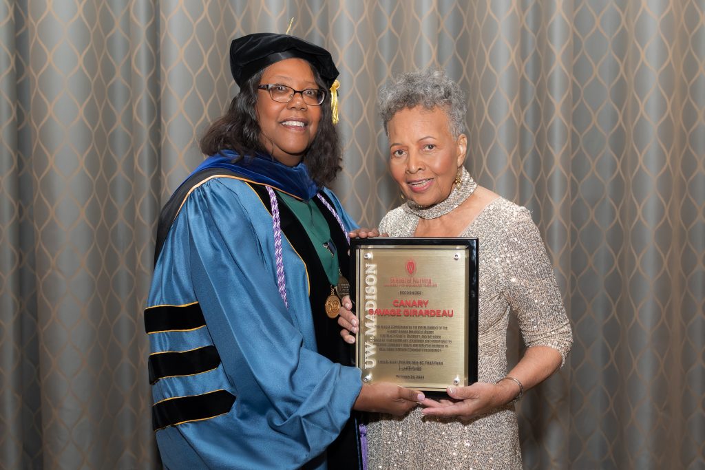 Dean Linda Scott presents Canary Savage Girardeau with a recognition plaque at the UW–Madison School of Nursing Investiture Ceremony.