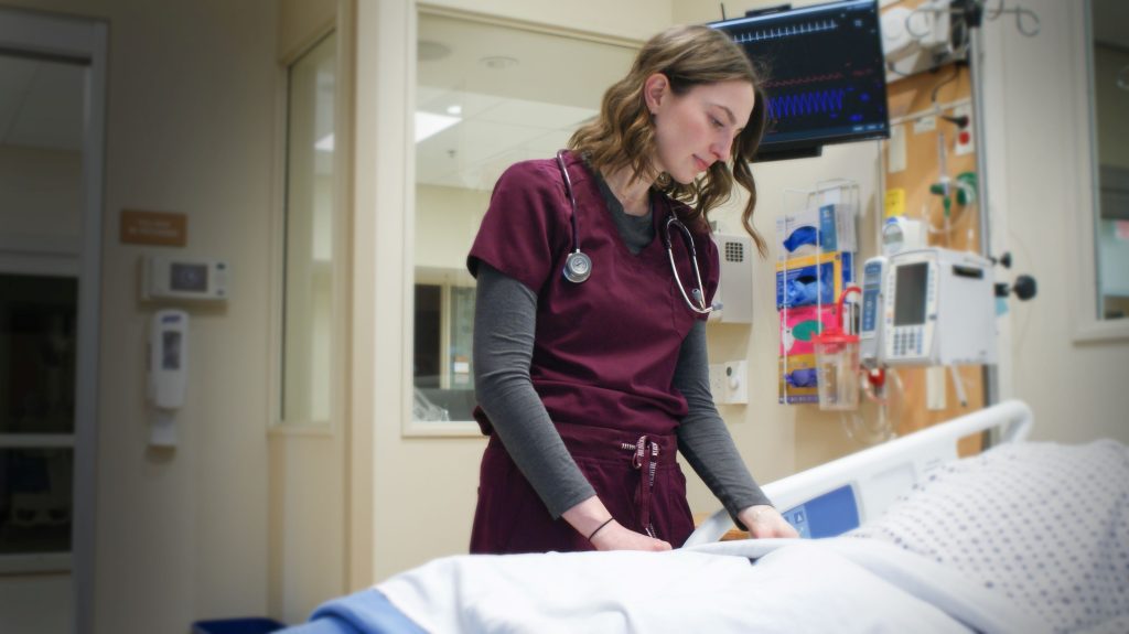 Emma Kowieski stands at the bedside of a patient.