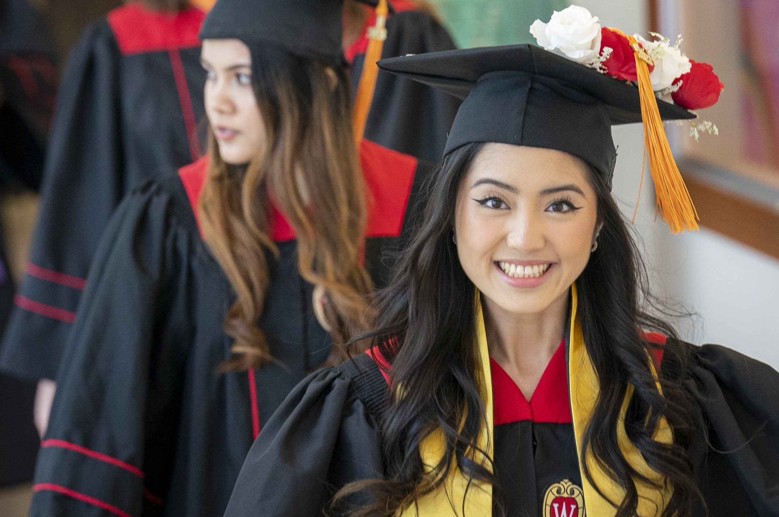 A graduate in cap and gown smiles at the camera.