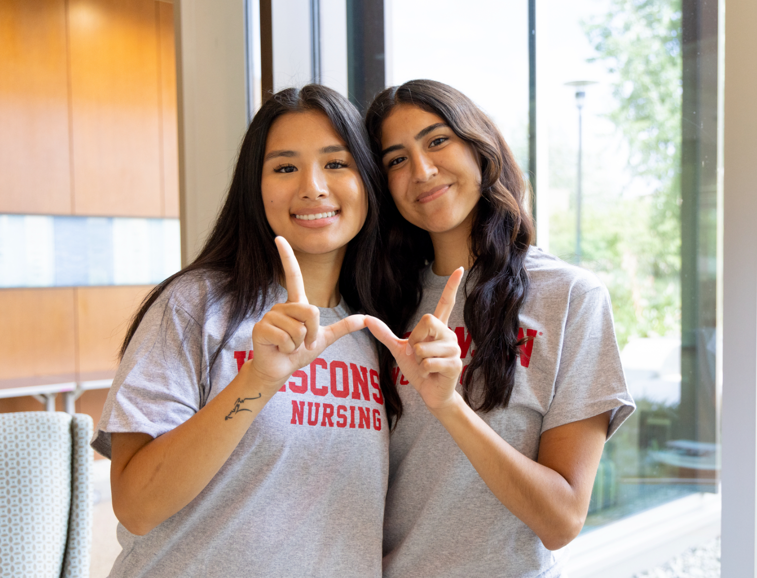 Rachelle and fellow student ambassador Sonam Dorjee hug while making the UW hand sign.