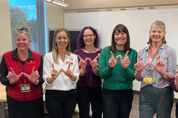 School of Nursing faculty make the W hand sign.