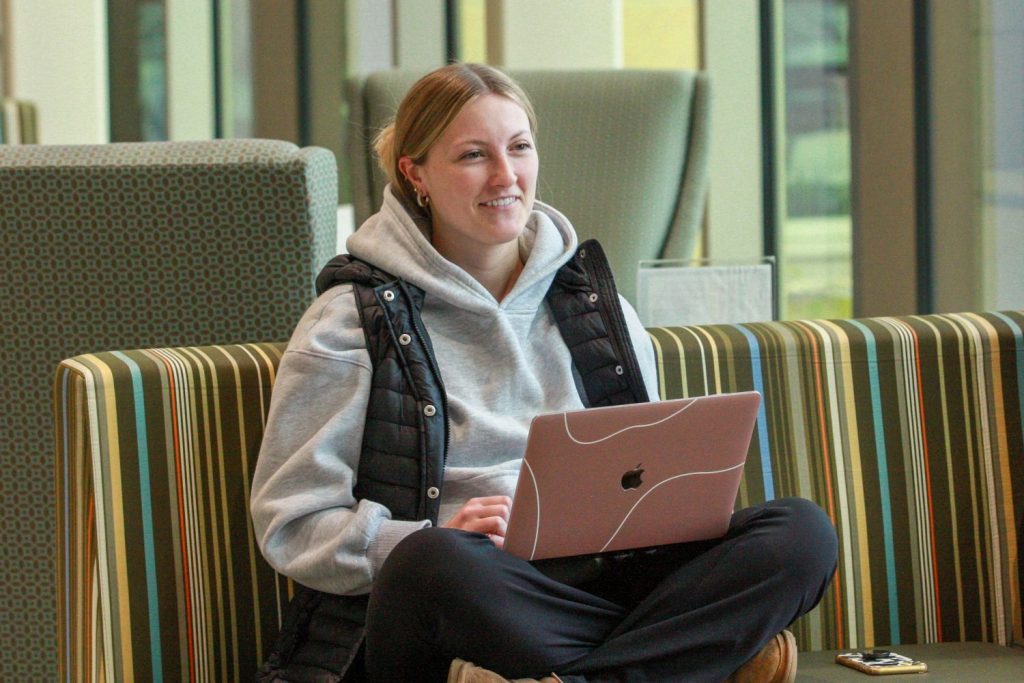 A student smiles while working on her laptop.