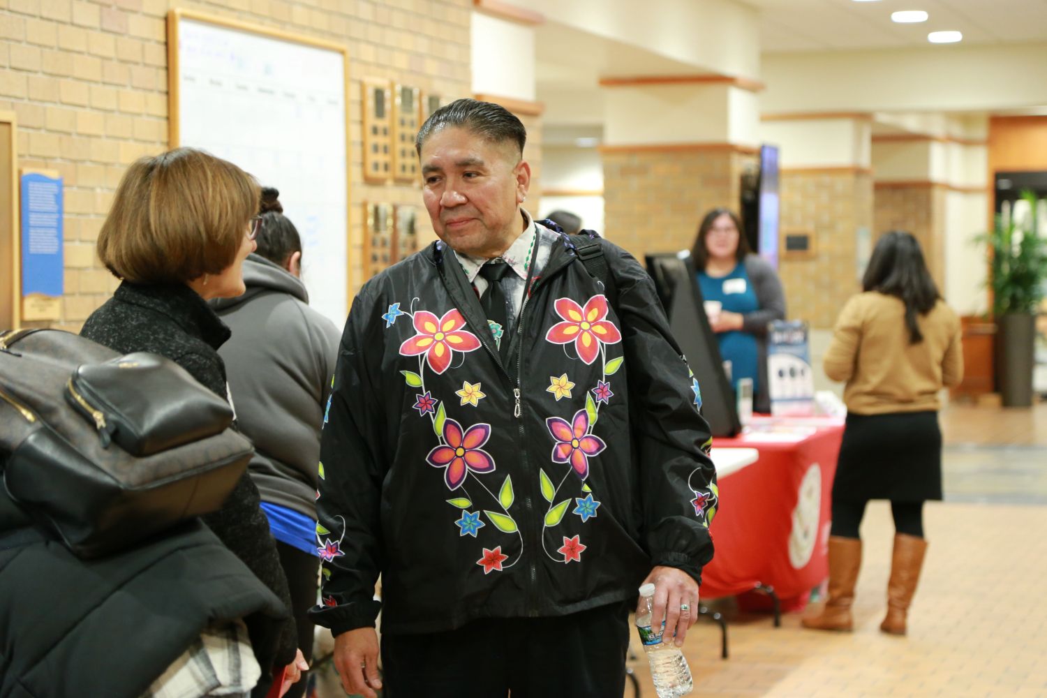 Brian Jackson, MS, EdD (Lac du Flambeau Band of Lake Superior Chippewa), Emcee of the 2024 Native Nations Nursing, Helpers, and Healers Summit chatting with a participant before the Summit began.