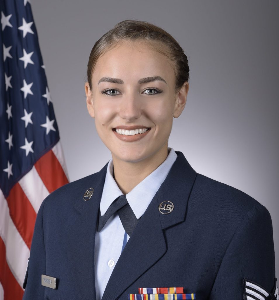 Mira Tcherneva in military uniform in front of the American flag.