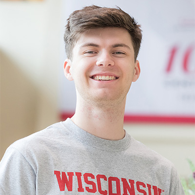 Headshot of Brandon Kreger from the waist up, wearing a gray t-shirt that says "Wisconsin Nursing" in red text.