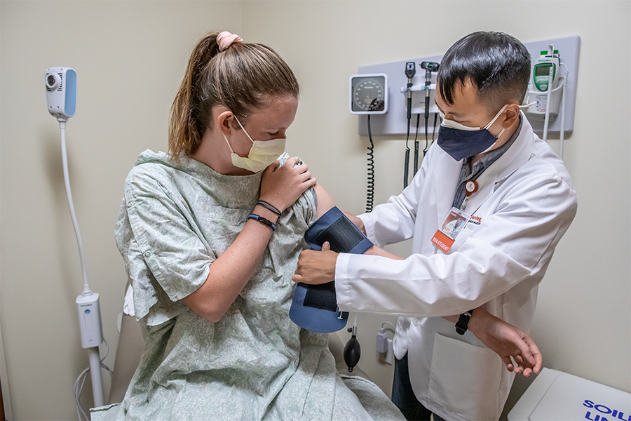 A UW-Madison ABSN student inspects a patient in a clinical setting.