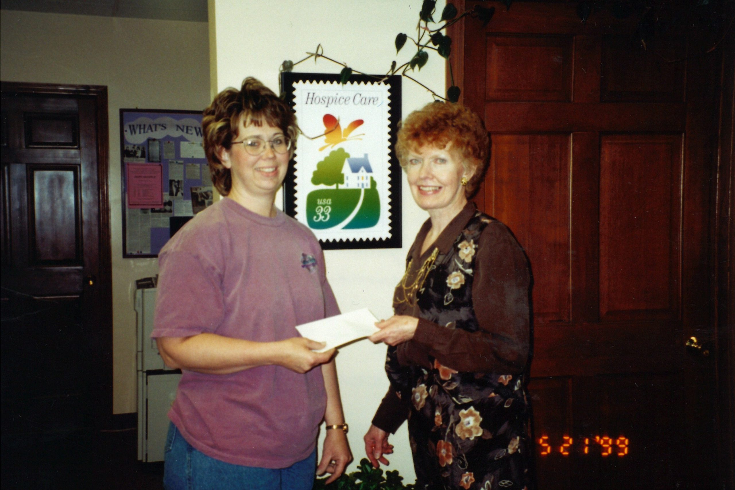 Meyer being presented with a generous check from one of her most faithful organizational donors, a snowmobile club. A plaque of the hospice stamp is in the background.