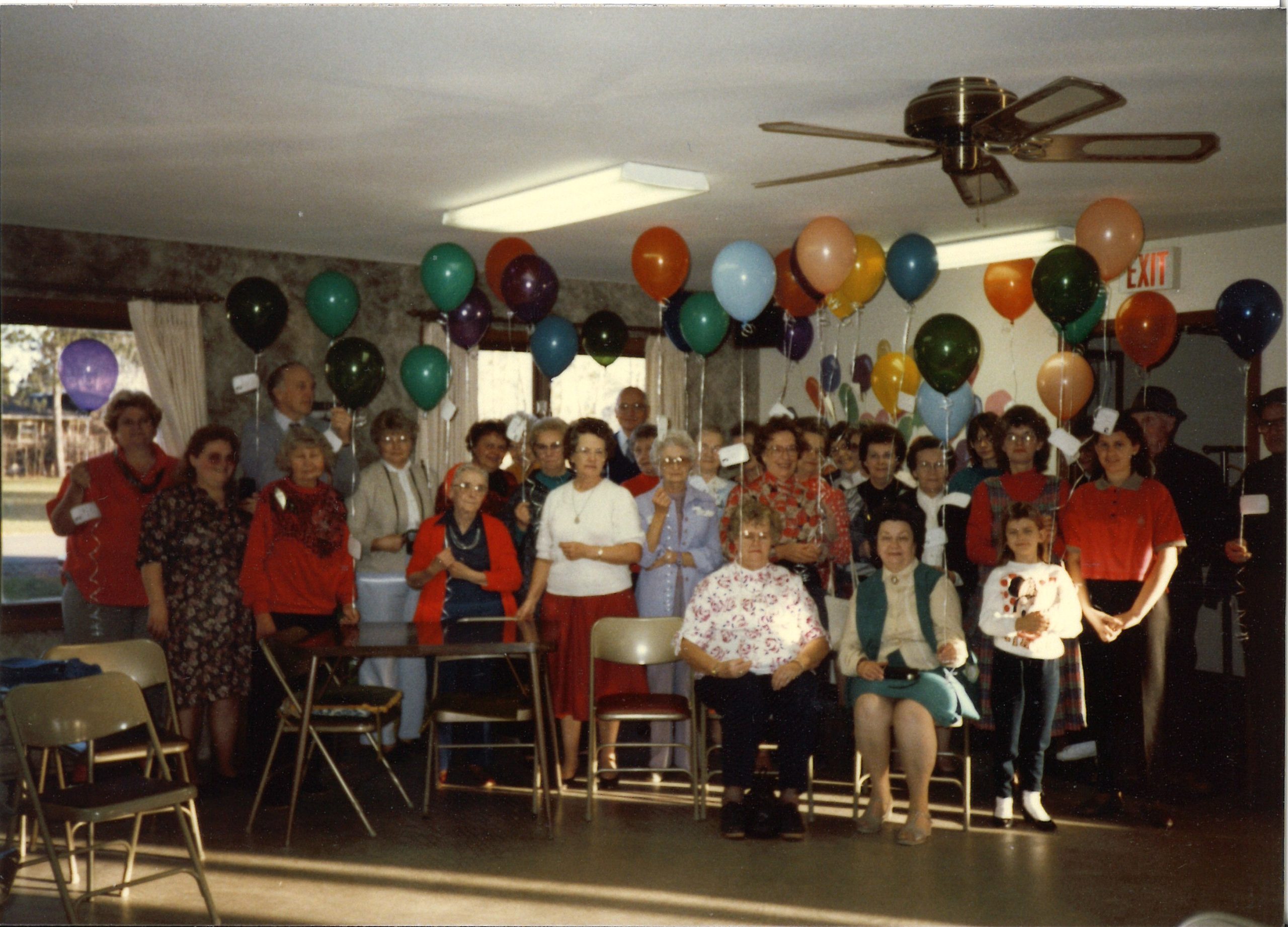 A group poses with many brightly colored balloons at a semi-annual memorial event to remember all the families cared for in the past year.