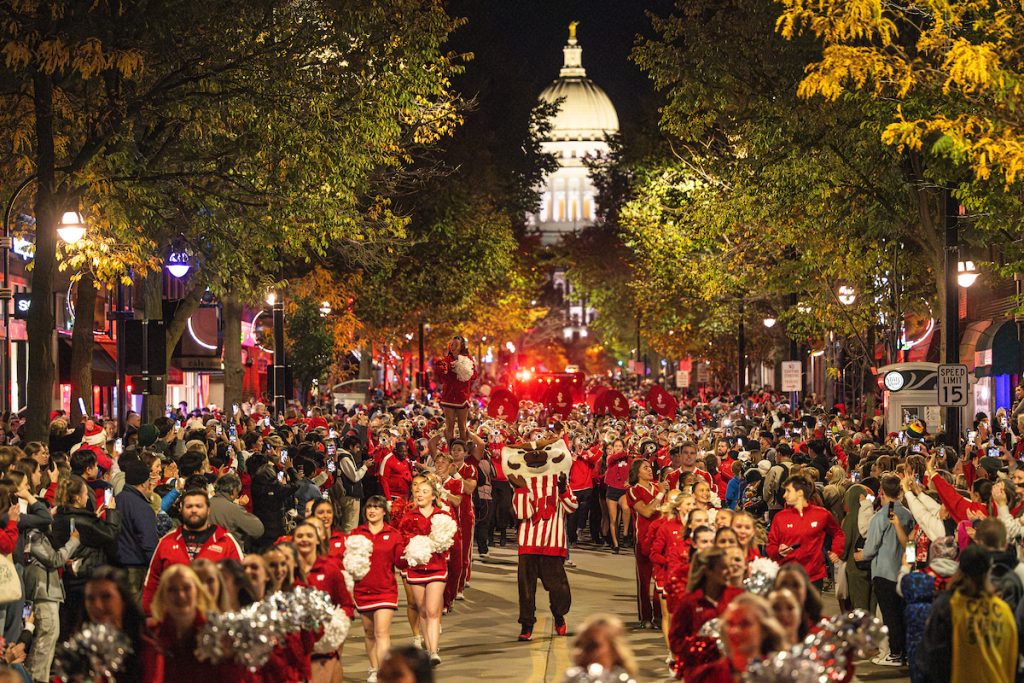 Bucky Badger and members of the UW Spirit Squad travel down State Street during the University of Wisconsin–Madison’s Homecoming Parade. The capitol dome can be seen in the background.