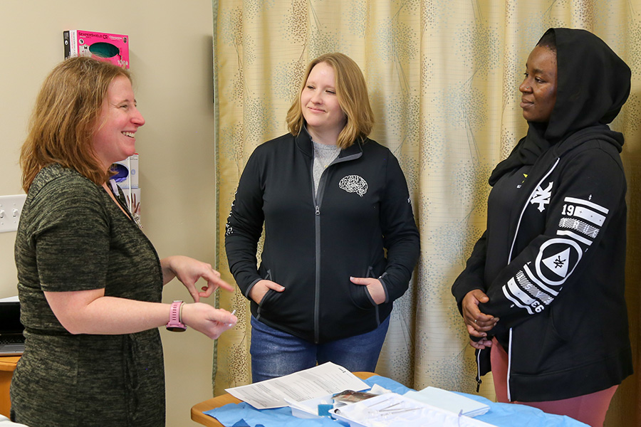 DNP students listen to their instructor during an acute care skills class in the clinical simulation environment.