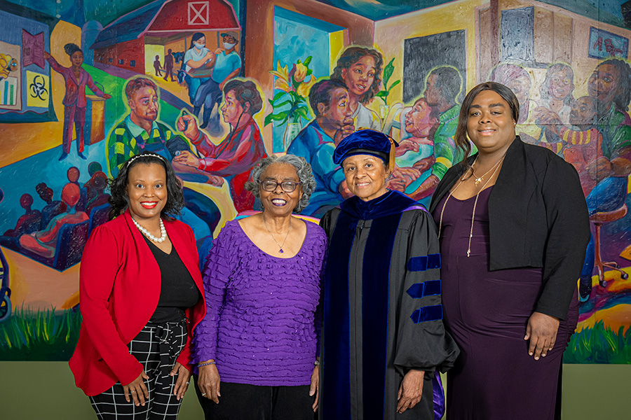 Associate Dean for Health Equity and Community Engagement Diamond D. Williams, and Health Equity and Community Engagement Specialist Demi Jo Carr stand with past award winners Edith Lawrence-Hilliard and Linda D. Oakley in front of the mural in Cooper Hall.