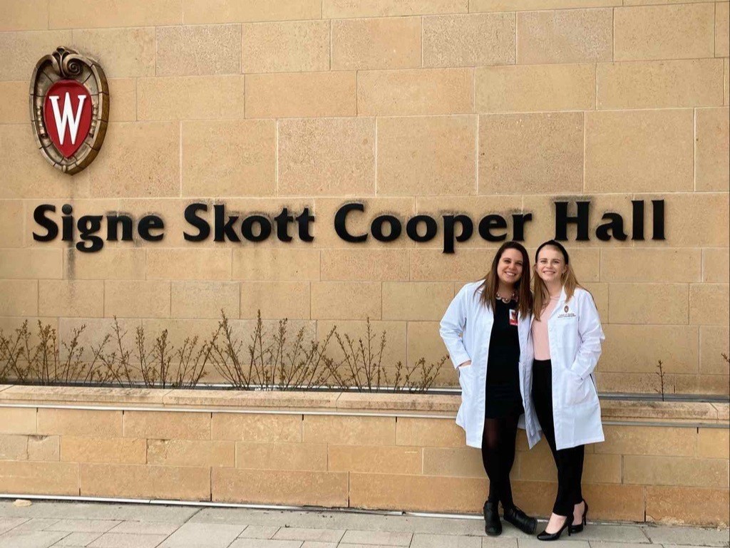 Stanek and a friend pose in their white coats in front of Signe Skott Cooper Hall.