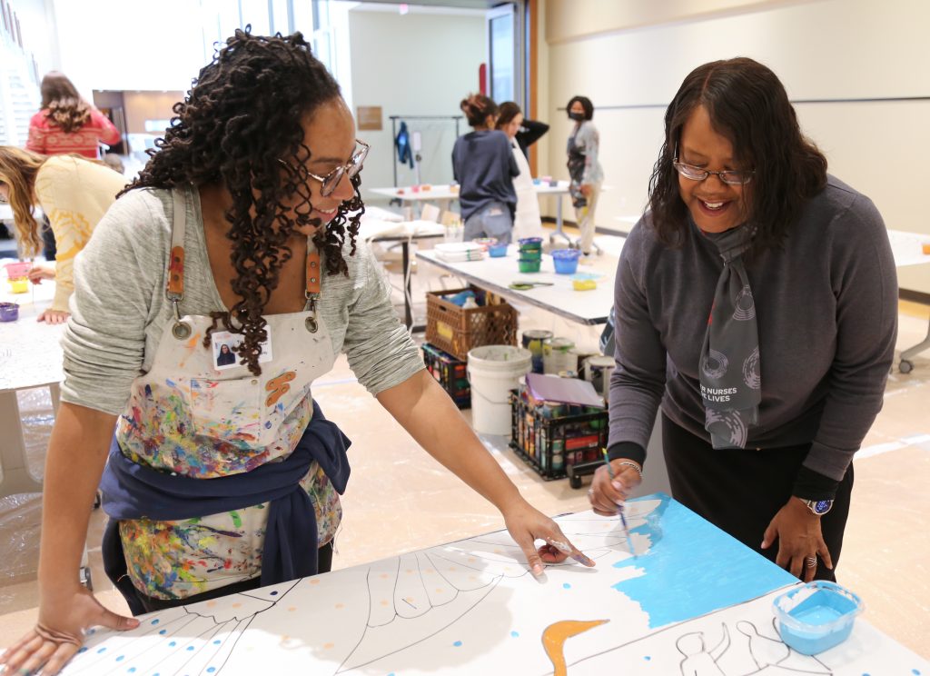 Linda D. Scott helps paint the School of Nursing's centennial mural with artist Tia Richardson.
