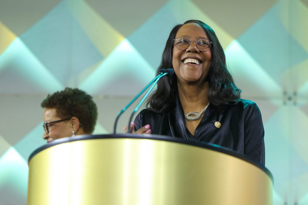 Dean Emerit Scott smiles as she gives an address at a golden podium during the 2025 AAN conference.
