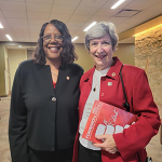 Dean Emerit Scott and Laurie Glass pose for a photo. Laurie holds the centennial issue of ForwardNursing magazine.