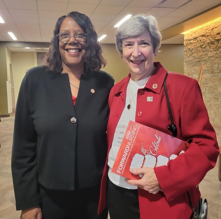 Dean Emerit Scott and Laurie Glass pose for a photo. Laurie holds the centennial issue of ForwardNursing magazine.