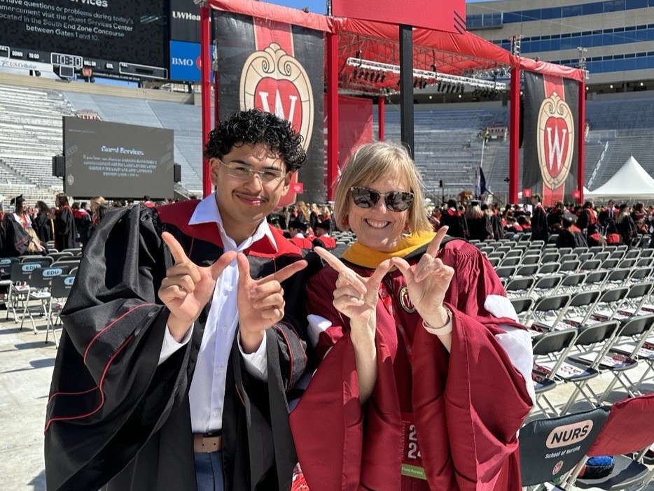 Judy Christensen and a graduating nursing student make the W hand sign at Camp Randall Stadium during graduation.