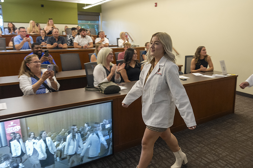 Macy Deaton walks past family and supporters of the traditional BSN class of 2026 during the White Coat Ceremony.