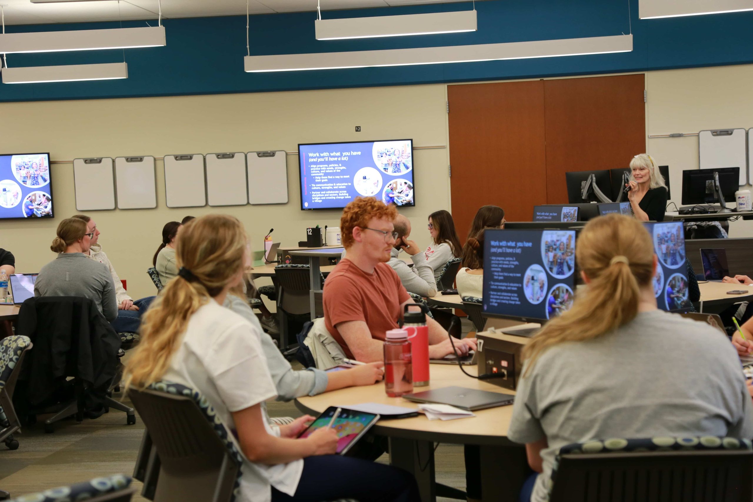Students sit around small tables while listening to a lecture in one of the state-of-the-art Active Learning Classrooms at Cooper Hall.