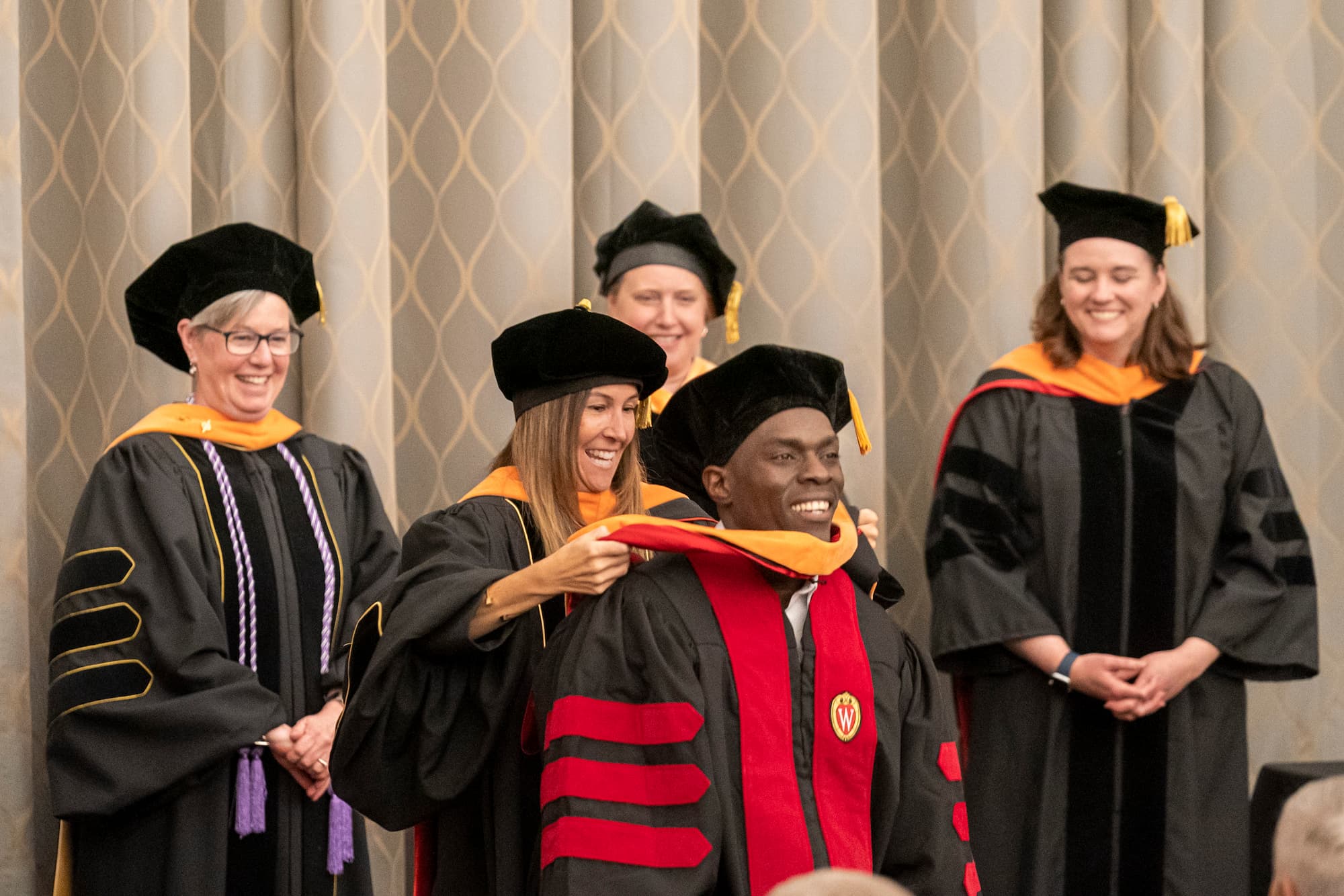 A DNP graduate beams as he receives his hood from faculty during the annual graduate hooding ceremony.