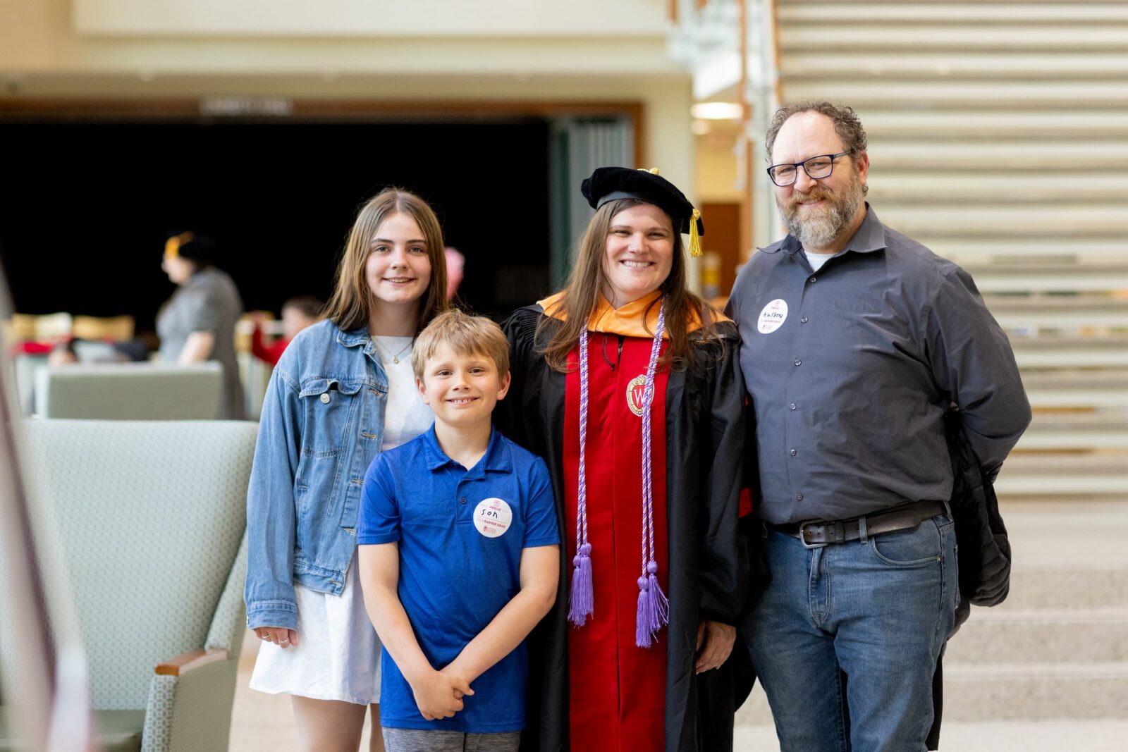 DNP graduate in her organ hood stands with partner and two children.