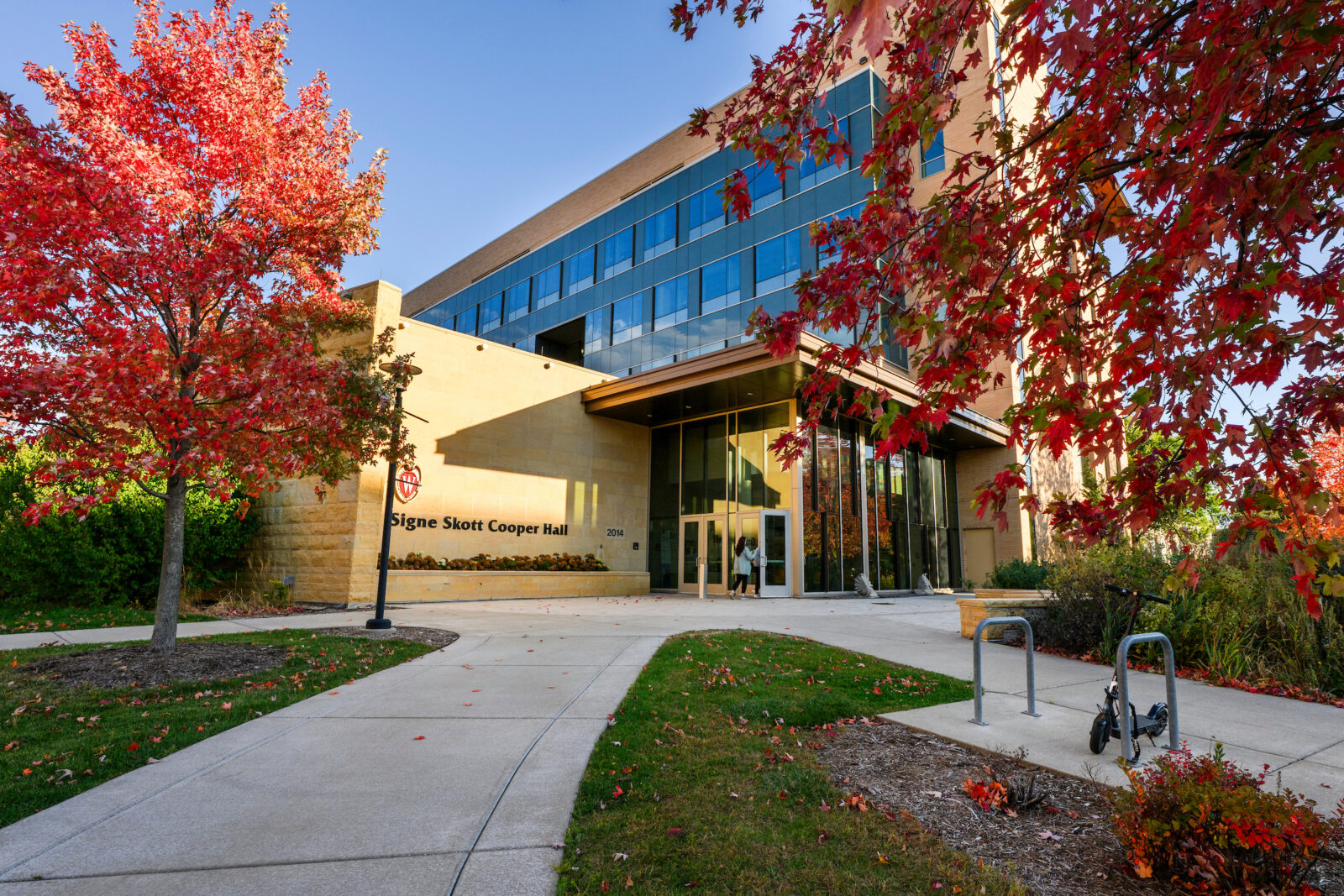 Fall foliage frames pedestrians entering Signe Skott Cooper Hall during an autumn day at the University of Wisconsin–Madison on Oct. 20, 2025. (Photo by Taylor Wolfram / UW–Madison)