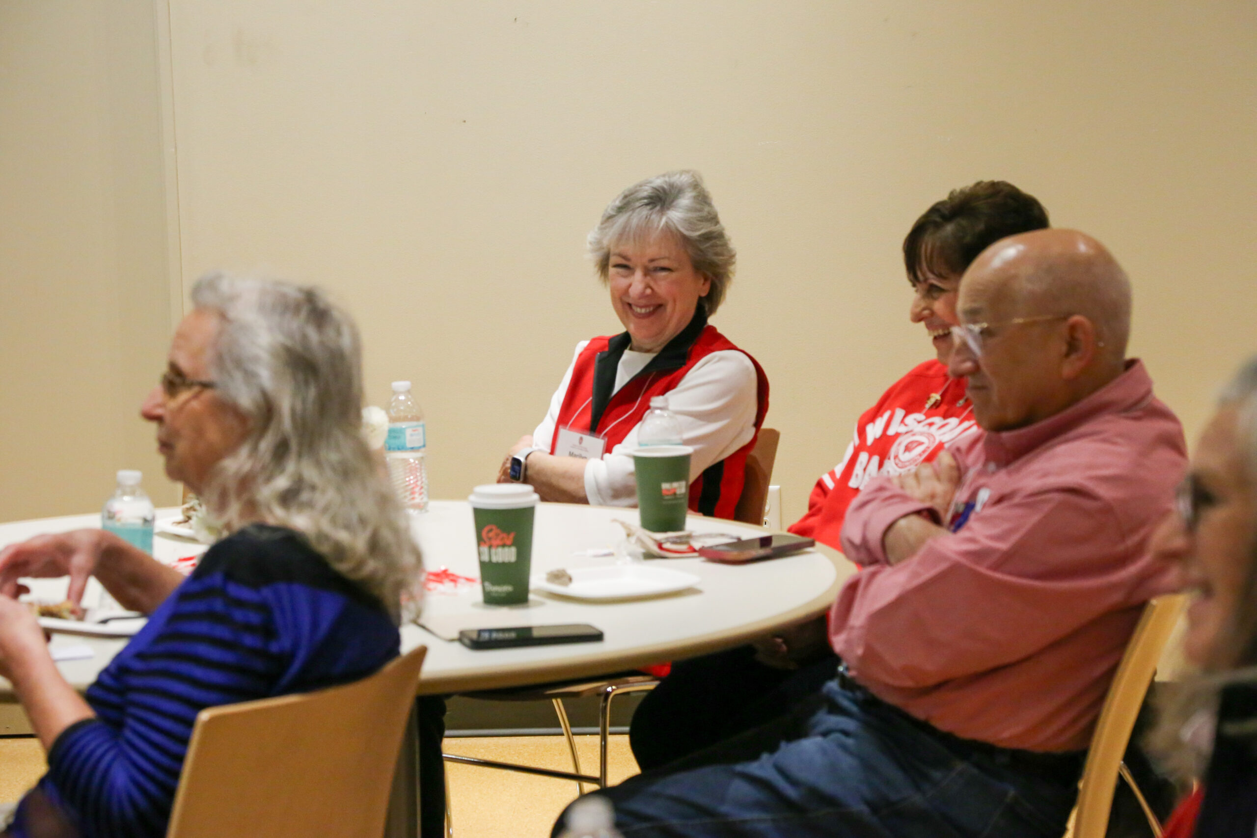 A Class of 1976 alumni smiles as she sits at a table with classmates during their 50th reunion.